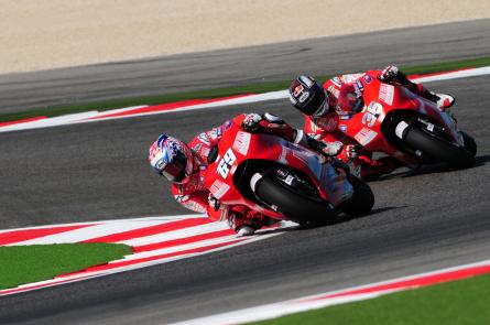 Due motociclisti in gara su una pista, piegando in curva.